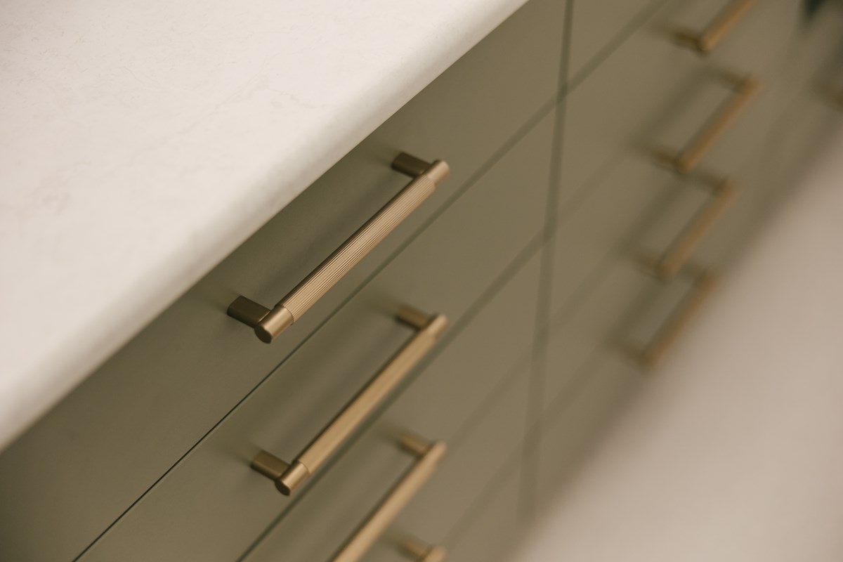 close up of dark green cabinetry with brass handles 